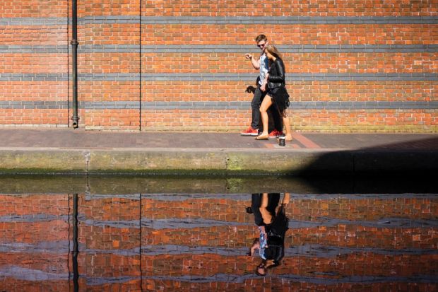 Young couple walking along canal with reflection on water Young couple walking along canal with reflection on water
