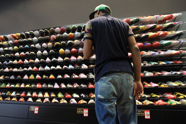 Young man looking at store display of sneakers/trainers Young man looking at store display of sneakers/trainers