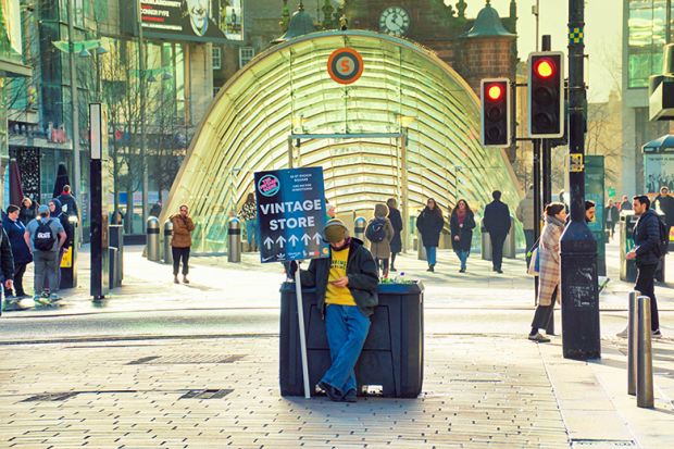 Young person holding a sandwich board advert, Glasgow. To illustrate that most students are employed in low-paid jobs. 