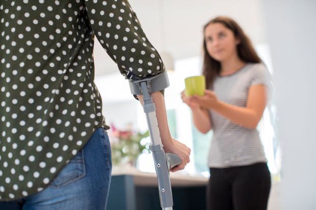A young carer makes a drink for her disabled parent