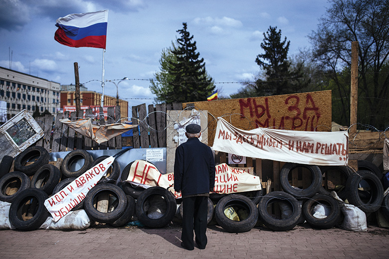 An elderly man stands next a barricade in the eastern Ukrainian city of Luhansk